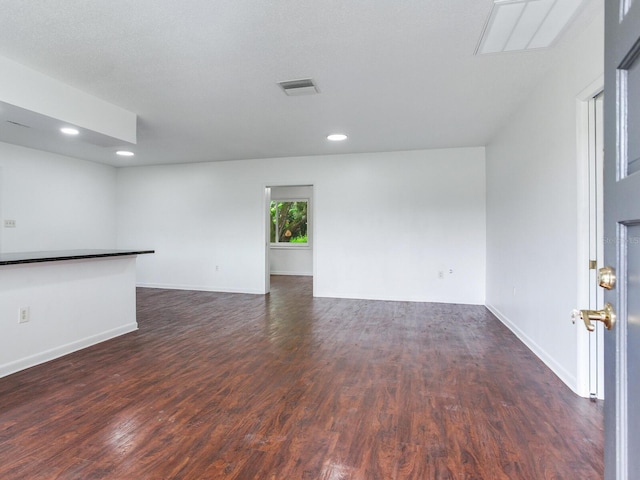 spare room with a textured ceiling and dark hardwood / wood-style flooring