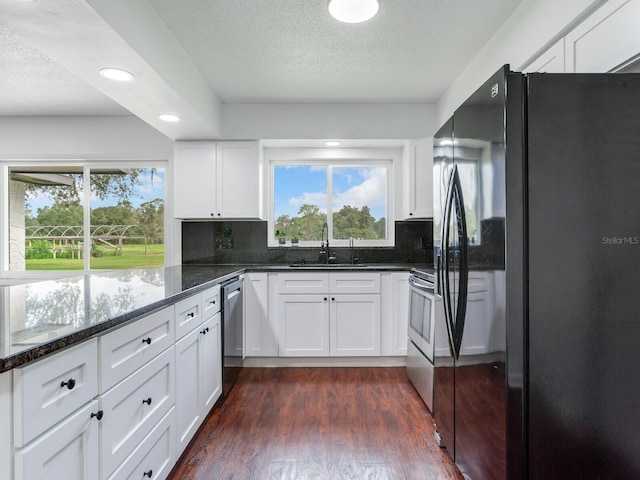 kitchen with appliances with stainless steel finishes, white cabinets, dark hardwood / wood-style flooring, and a wealth of natural light