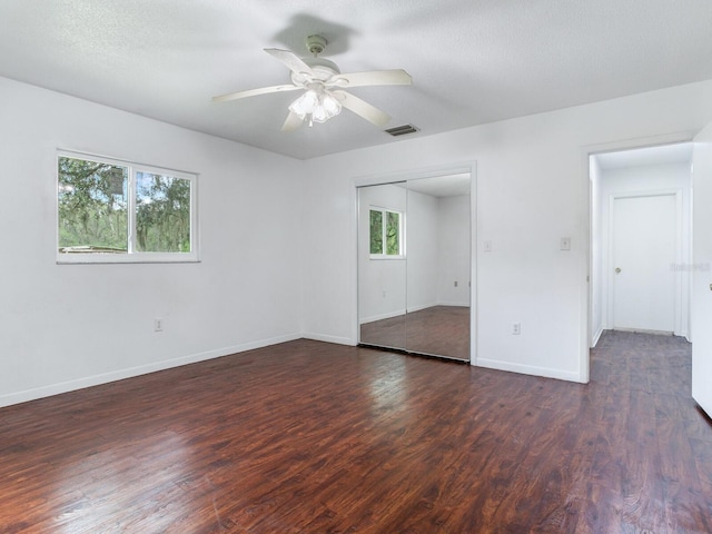 empty room featuring a healthy amount of sunlight, dark hardwood / wood-style floors, and ceiling fan