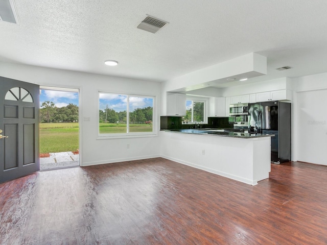 kitchen with white cabinetry, kitchen peninsula, appliances with stainless steel finishes, and plenty of natural light