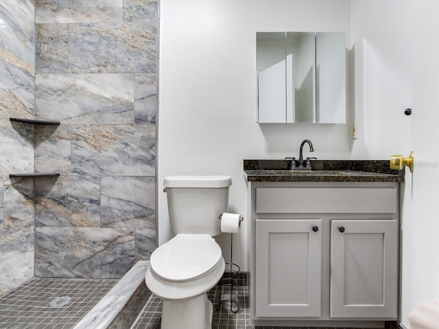 bathroom featuring a tile shower, vanity, toilet, and tile patterned floors