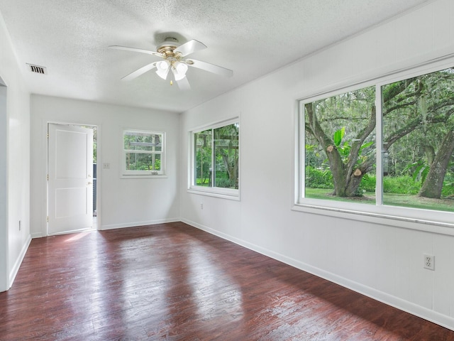 empty room with a textured ceiling, dark hardwood / wood-style floors, and ceiling fan