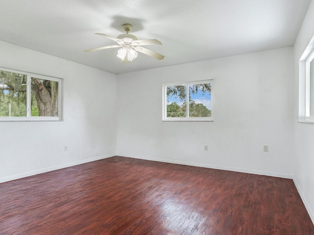 empty room with ceiling fan, dark wood-type flooring, and a healthy amount of sunlight