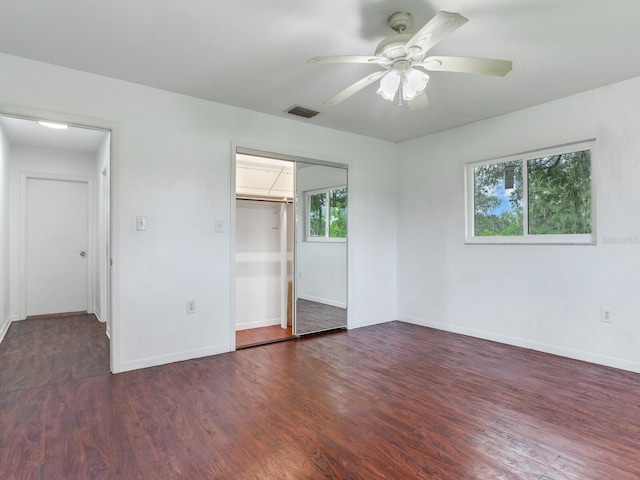 unfurnished bedroom featuring ceiling fan, dark hardwood / wood-style flooring, and multiple windows