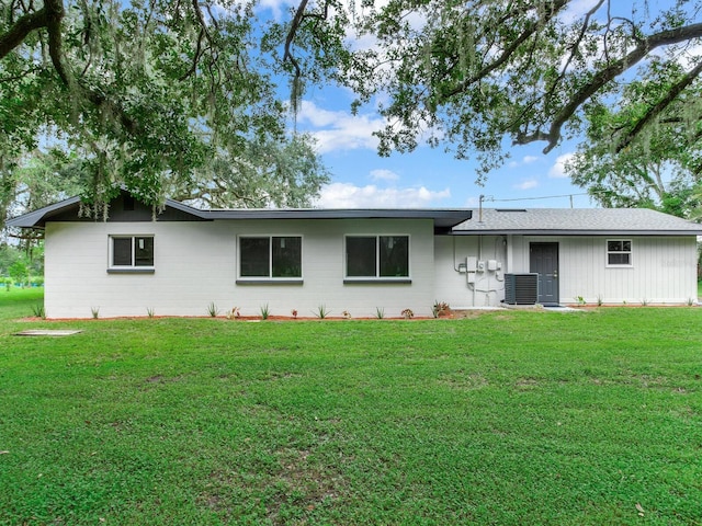 rear view of property featuring a lawn and central AC