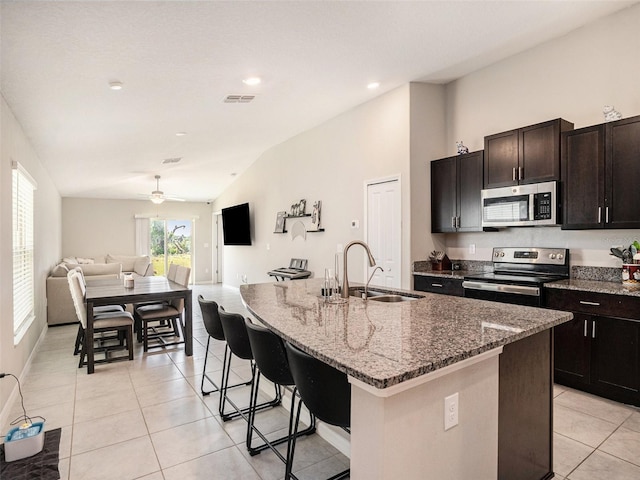 kitchen with appliances with stainless steel finishes, vaulted ceiling, sink, and an island with sink