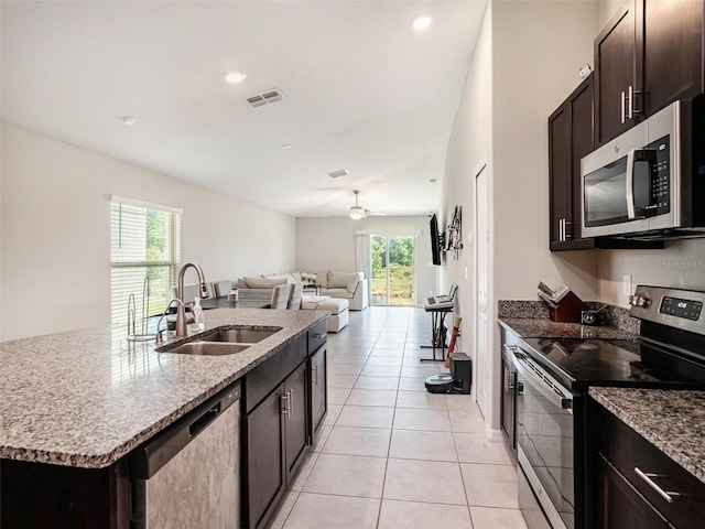 kitchen featuring sink, a center island with sink, appliances with stainless steel finishes, light tile patterned floors, and ceiling fan