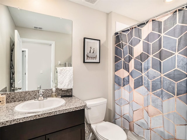 bathroom with walk in shower, vanity, and toilet