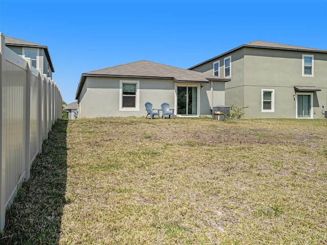 rear view of property featuring a lawn and central air condition unit