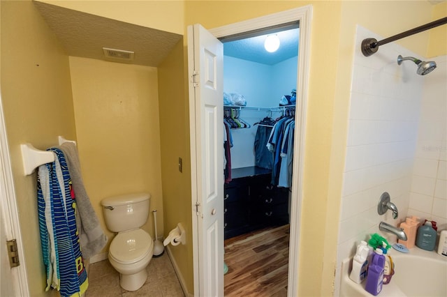 bathroom featuring tiled shower / bath, a textured ceiling, toilet, and hardwood / wood-style flooring