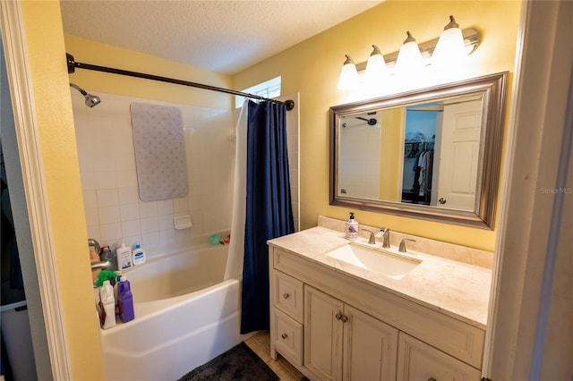 bathroom with a textured ceiling, shower / bathtub combination with curtain, and vanity