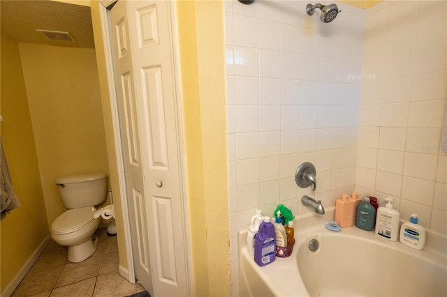 bathroom with tiled shower / bath, tile patterned flooring, and toilet