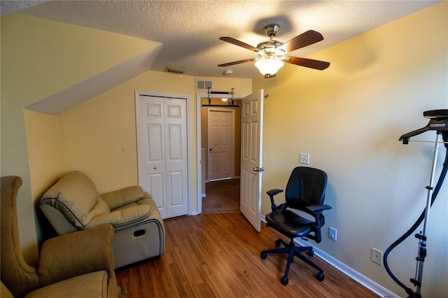 office featuring ceiling fan, vaulted ceiling, a textured ceiling, and hardwood / wood-style floors