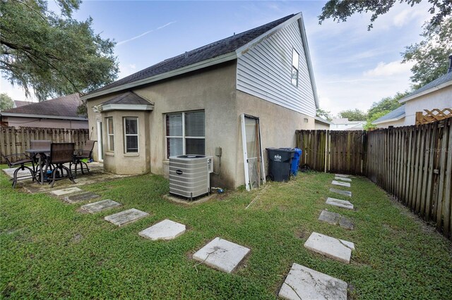 back of property with central AC unit, a yard, and a patio area