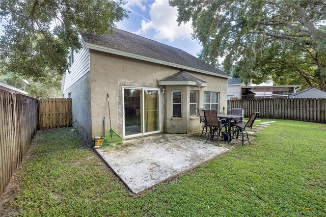 back of property featuring a lawn and a patio