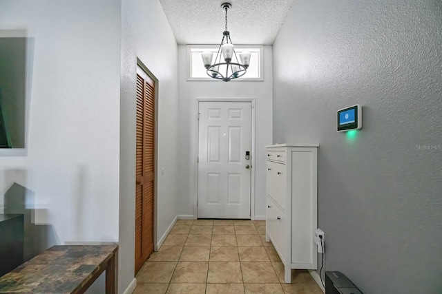 doorway to outside featuring a textured ceiling, light tile patterned floors, and a notable chandelier