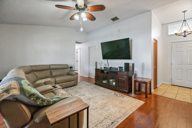 living room with a textured ceiling, ceiling fan with notable chandelier, hardwood / wood-style floors, and high vaulted ceiling