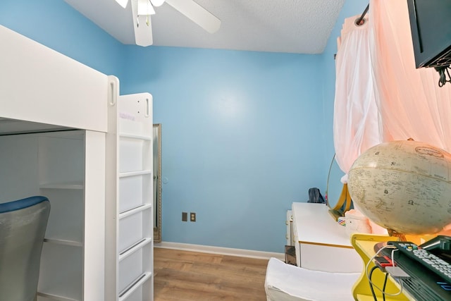 bedroom with ceiling fan, a textured ceiling, and light hardwood / wood-style floors