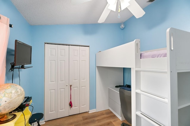 bedroom with ceiling fan, a textured ceiling, light hardwood / wood-style flooring, a closet, and vaulted ceiling