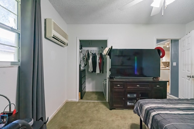 carpeted bedroom with an AC wall unit, a closet, ceiling fan, and a textured ceiling