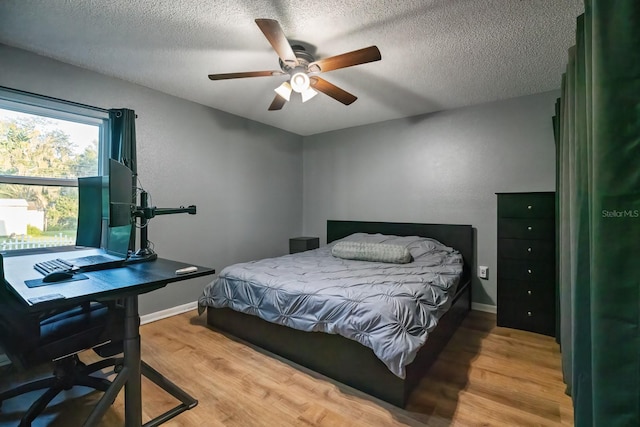 bedroom featuring ceiling fan, hardwood / wood-style floors, and a textured ceiling