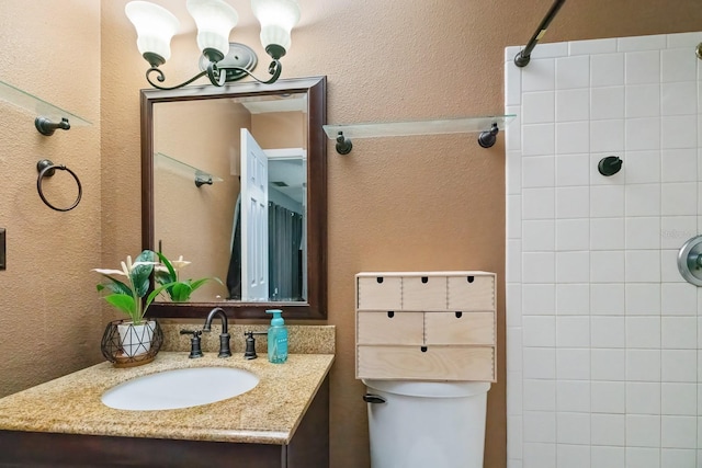 bathroom featuring a tile shower, vanity, and toilet