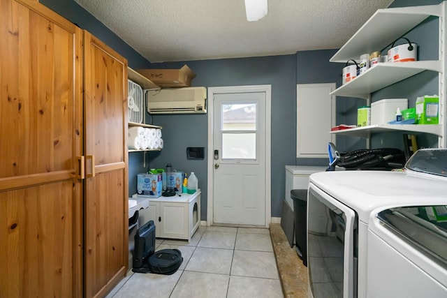 laundry room featuring a textured ceiling, light tile patterned floors, washing machine and dryer, and a wall mounted AC