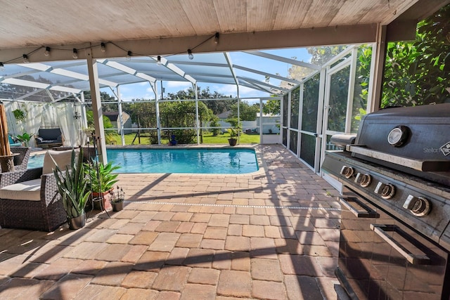 view of pool with a grill, glass enclosure, and a patio area