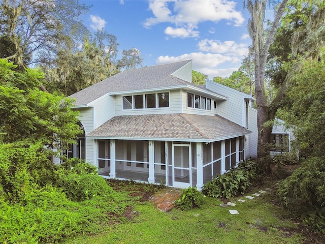 rear view of house featuring a sunroom and a lawn