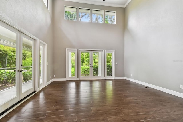 unfurnished living room featuring a towering ceiling, plenty of natural light, and french doors