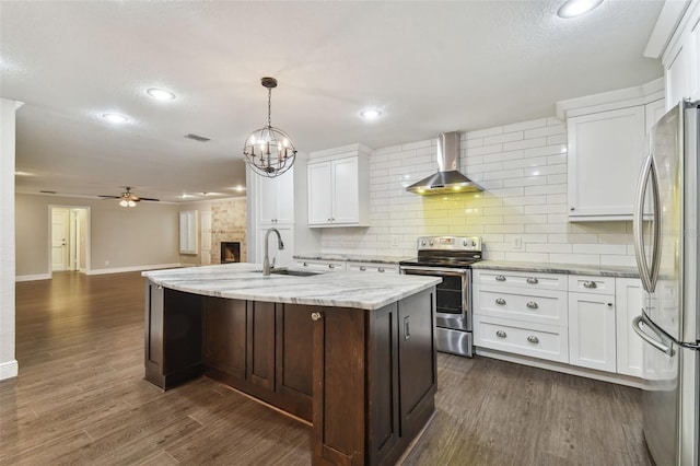 kitchen featuring appliances with stainless steel finishes, dark hardwood / wood-style floors, white cabinetry, sink, and wall chimney exhaust hood