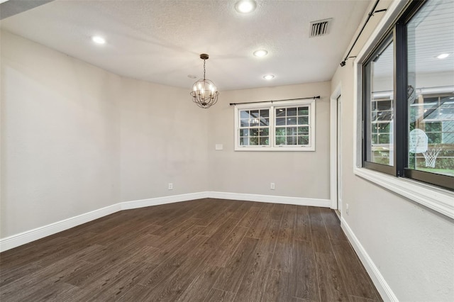 unfurnished room with dark wood-type flooring, a notable chandelier, and a textured ceiling