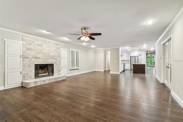 unfurnished living room with ceiling fan, a fireplace, ornamental molding, a textured ceiling, and dark hardwood / wood-style flooring