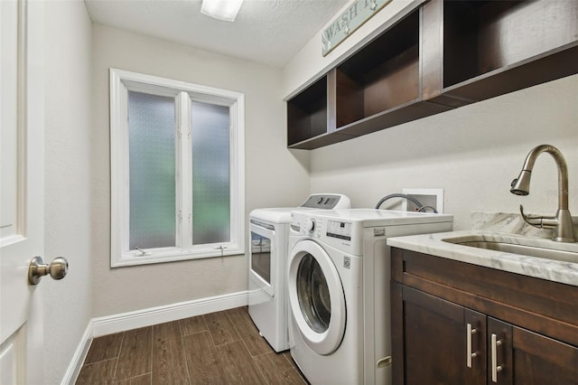 laundry area with cabinets, washer and dryer, sink, and a textured ceiling