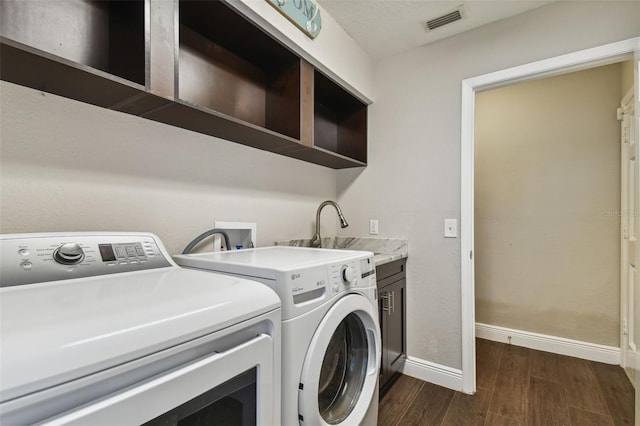 laundry area with sink, dark hardwood / wood-style floors, washer and clothes dryer, and cabinets