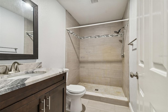 bathroom with vanity, toilet, tile patterned flooring, and a tile shower