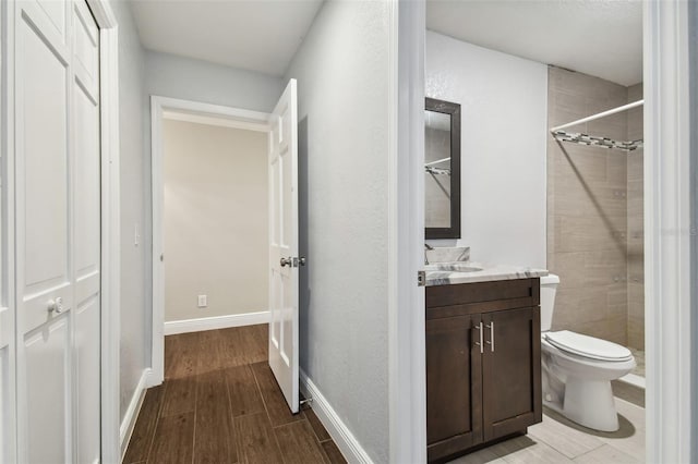 bathroom with vanity, a tile shower, and toilet