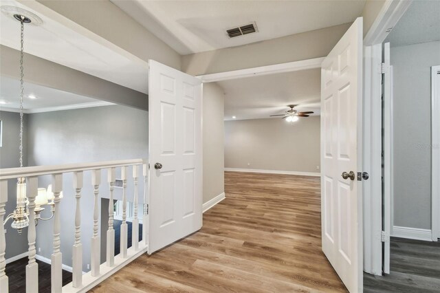 corridor with an inviting chandelier, wood-type flooring, and crown molding