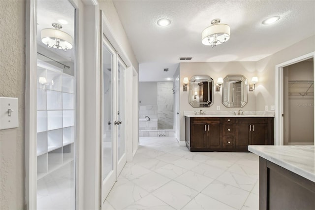 bathroom featuring walk in shower, vanity, and a textured ceiling