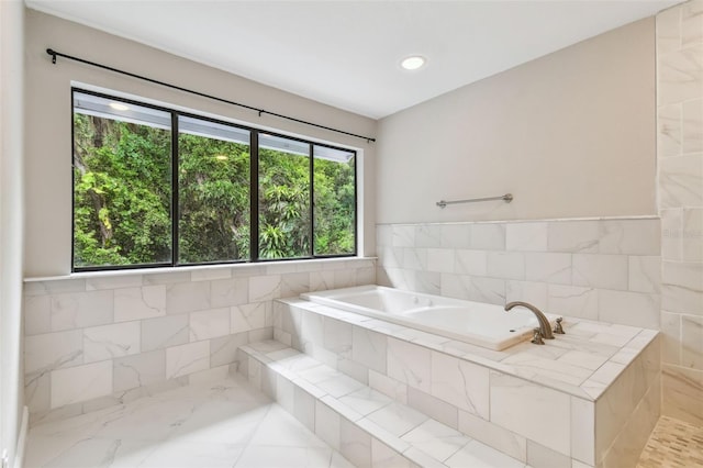 bathroom featuring a relaxing tiled tub and tile walls