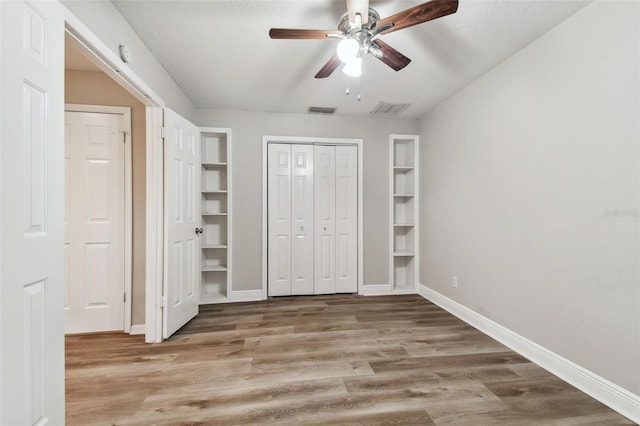 unfurnished bedroom featuring ceiling fan, wood-type flooring, and a textured ceiling