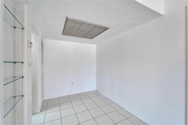 spare room with a textured ceiling and light tile patterned floors