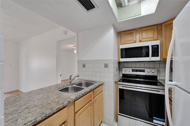 kitchen with light brown cabinetry, white appliances, sink, and light stone counters