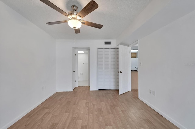 unfurnished bedroom with white refrigerator, light hardwood / wood-style floors, a textured ceiling, ensuite bath, and ceiling fan