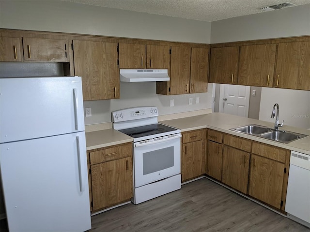 kitchen with a textured ceiling, white appliances, light hardwood / wood-style floors, and sink