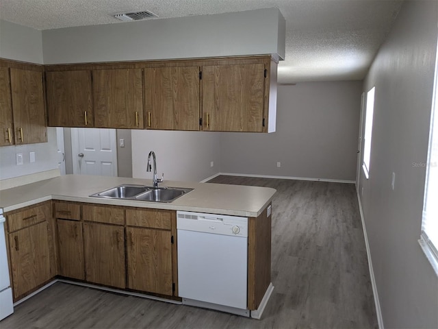 kitchen featuring kitchen peninsula, sink, a textured ceiling, dark wood-type flooring, and dishwasher