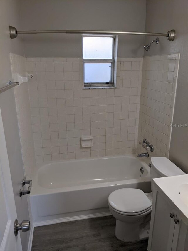 full bathroom featuring hardwood / wood-style floors, tiled shower / bath combo, vanity, and toilet