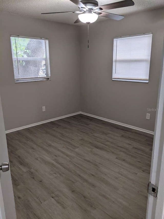 spare room featuring a wealth of natural light, ceiling fan, and dark hardwood / wood-style floors