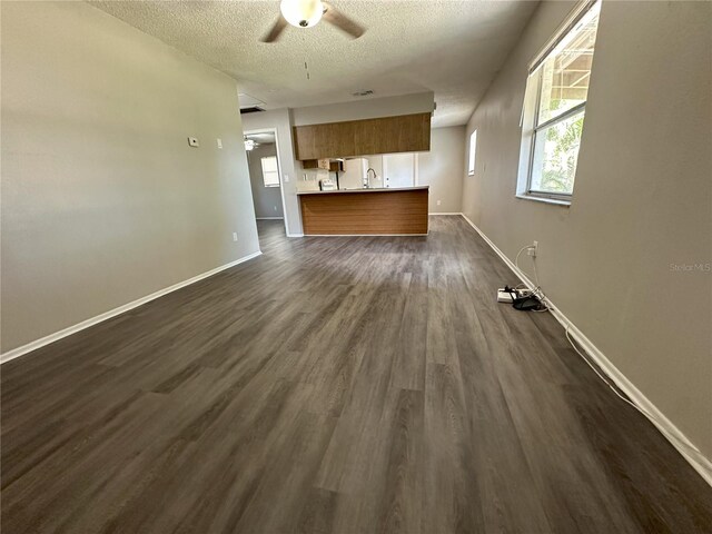 unfurnished living room with ceiling fan, a textured ceiling, dark hardwood / wood-style floors, and sink