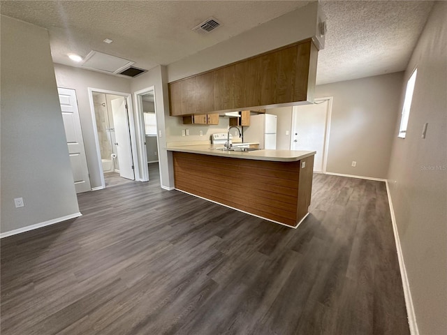 kitchen featuring a textured ceiling, kitchen peninsula, dark hardwood / wood-style flooring, and white refrigerator